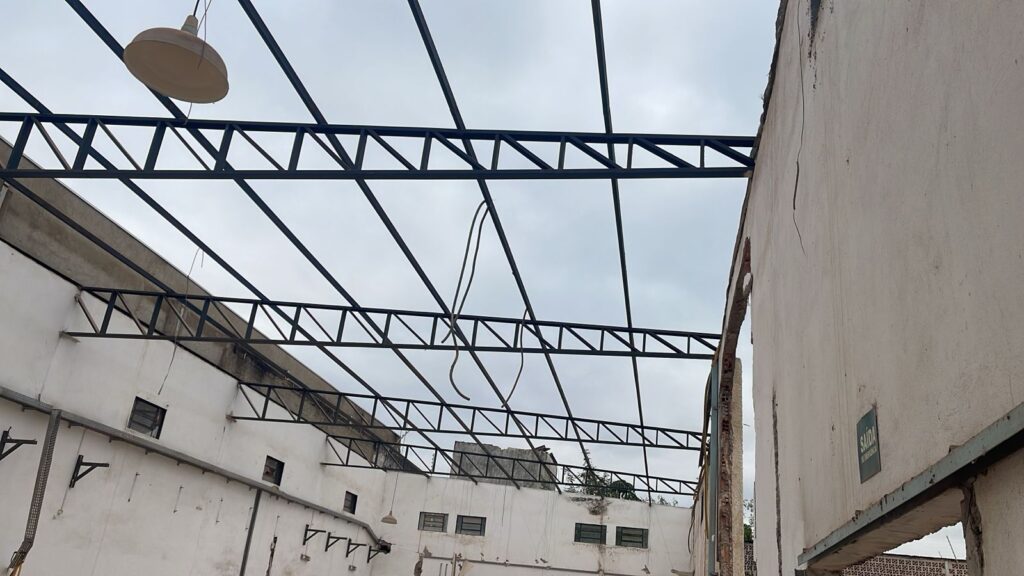 Nova estrutura de telhado metálico sobre alvenaria existente